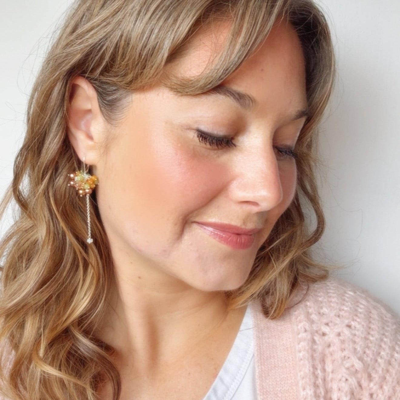 Close-up of a woman wearing beaded cluster dangle earrings with sterling silver.